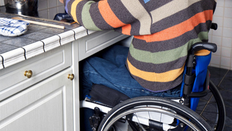 A man sitting in a wheelchair sits at a counter customized with a wheelchair space