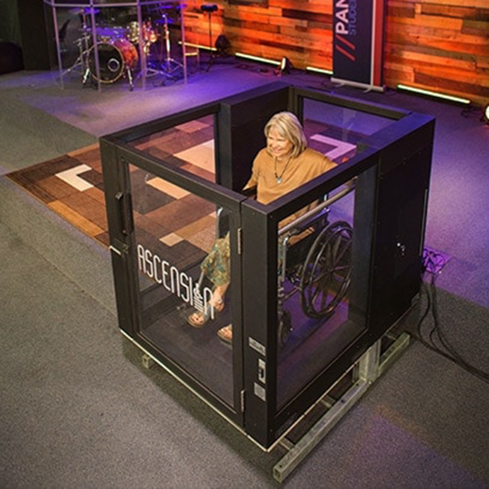 A woman in a wheelchair sits inside an Ascension Lift wheelchair lift