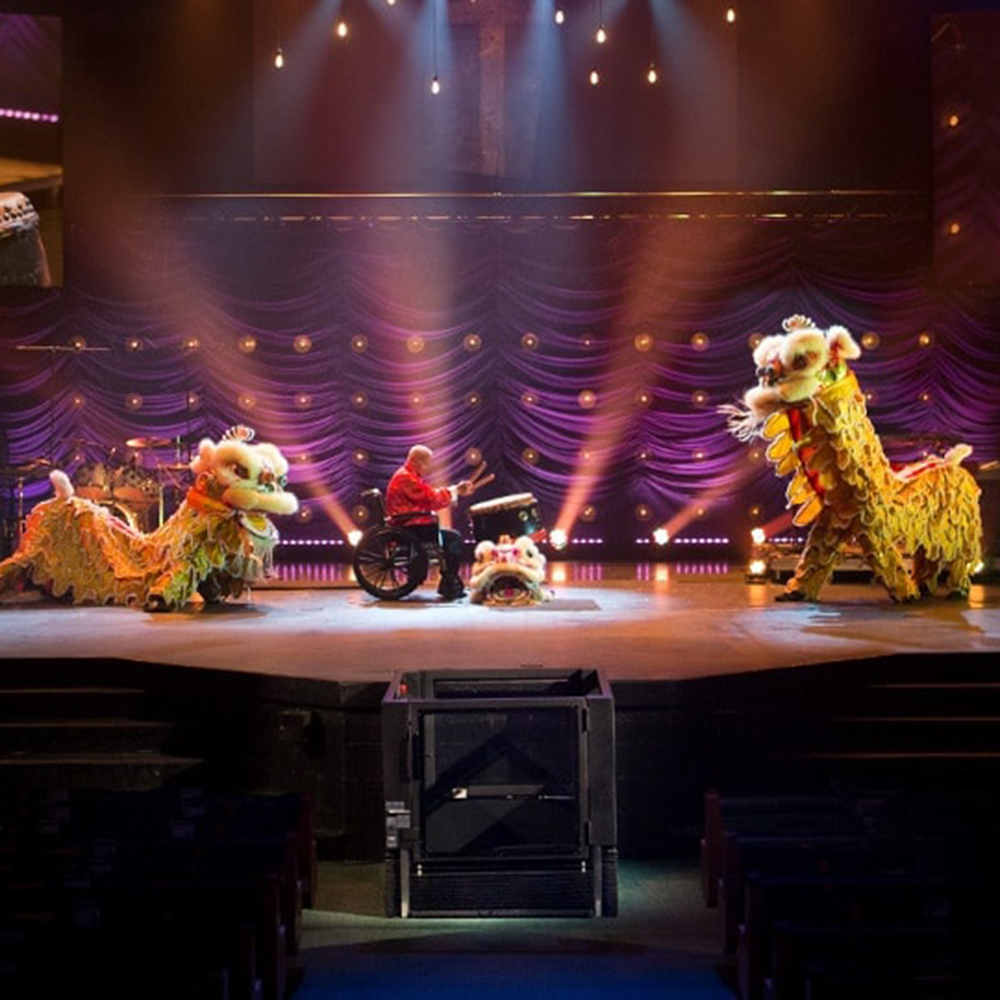 A Virtuoso wheelchair lift from Ascension Lift is seen beside a stage where a performance is taking place