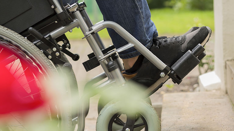 Man on a wheelchair trying to overcome the stairs barrier in the park